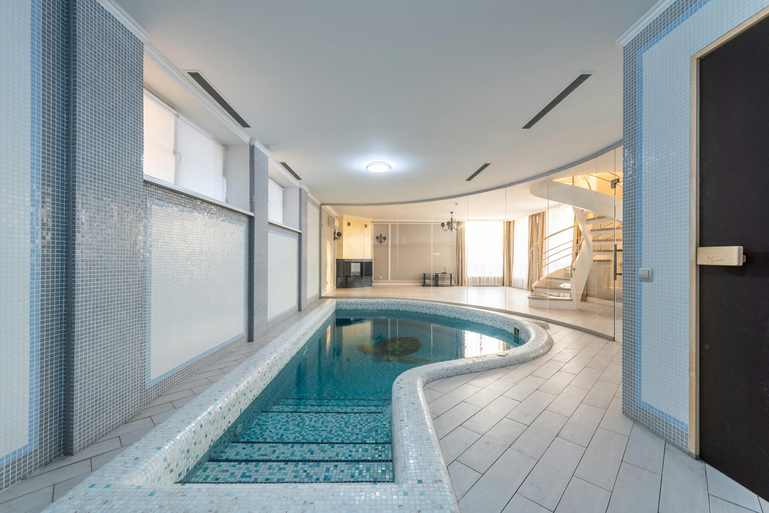 Serene indoor pool area with modern design and spiral staircase.